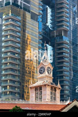 Clock tower of the 19th century Lau Pa Sat, also known as Telok Ayer Market against towering modern buildings in Robinson Road, Republic of Singapore. Stock Photo