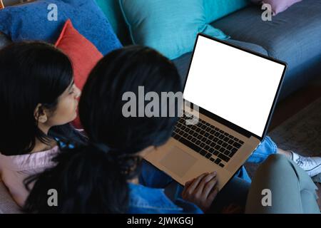 High angle view of biracial mother sitting with daughter using laptop on cough at home Stock Photo