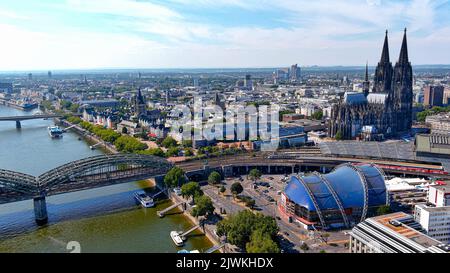 Aerial view of Cologne city on a sunny day. Famous landmark of gothic architecture Cologne Cathedral and Hohenzollern Bridge ft. central train station Stock Photo