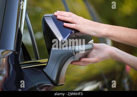 Driver hands adjusting side view mirror of a car. Stock Photo