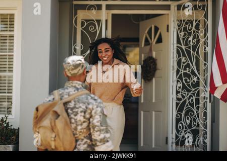Excited military wife welcoming her husband from the army. Happy military wife smiling cheerfully while running to embrace her husband on his homecomi Stock Photo