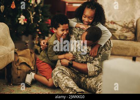 Army soldier playing with his children at Christmas. Happy military dad reuniting with his children at home. Soldier spending quality time with his fa Stock Photo