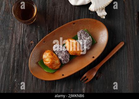 Gemblong or Kue Gemblong is Sticky Rice Cake Caoted with Liquid Palm Sugar, Indonesian Popular Street Food. Top View on Wooden Table Stock Photo