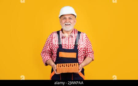 happy senior man bricklayer in hard hat on yellow background Stock Photo