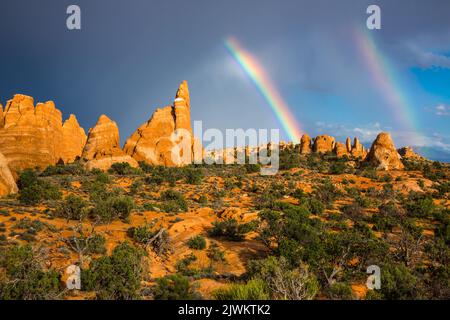 A partial rainbow with virga over Entrada sandstone fins in the Devil's Garden, Arches National Park, Moab, Utah. Stock Photo