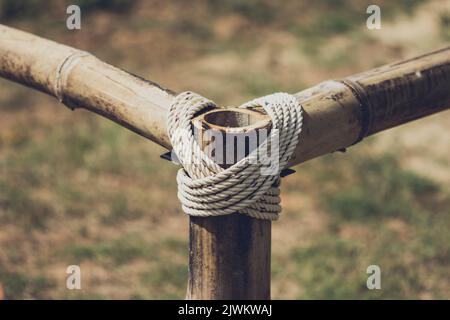 Coarse rope wrapped around wooden pole in vintage color.Blured background with a natural sunlight Stock Photo