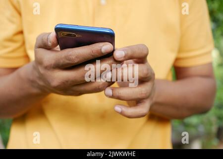 young man in yellow shirt using smart phone. Stock Photo