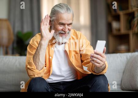 Cheerful elderly man having video call with family, using smartphone Stock Photo