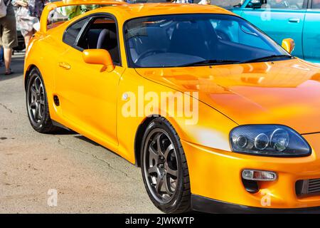 Front end with headlight of yellow modern sport car in sunset on blurred city background. transport concept. Travel and carsharing concept. selective Stock Photo