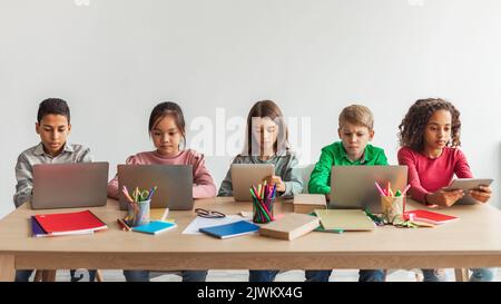 Five Multiethnic School Kids Using Laptops In Classroom, Panorama Stock Photo