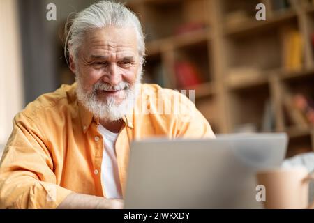 Closeup of happy old man using notebook at home Stock Photo