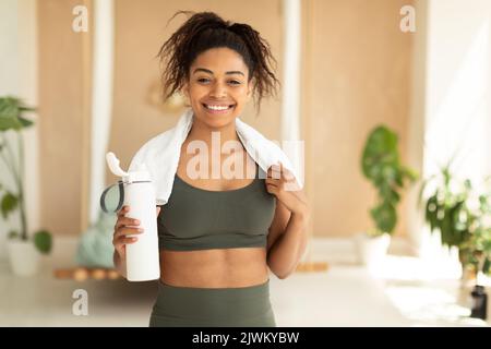 Nutrition for sport and exercise. Happy african american woman with white towel on neck holding shaker with protein Stock Photo