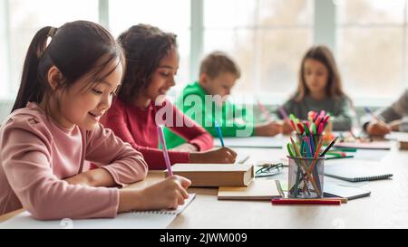 Japanese Schoolgirl Taking Notes Writing Essay Learning In Classroom, Panorama Stock Photo