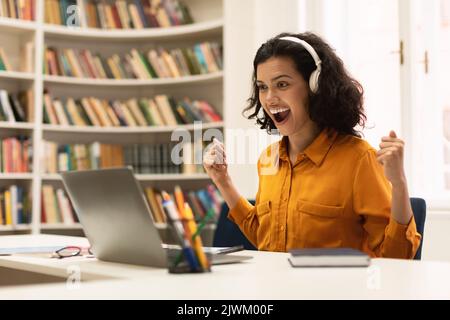 Joyful woman celebrating success with laptop, female student looking at computer screen and exclaiming with excitement Stock Photo