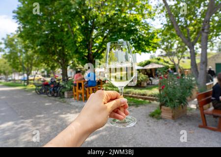 holding a glass of wine with a sign of the vine village Purbach am Neusiedlersee old traditional village in Purbach Austria next to Lake Neusiedl Stock Photo