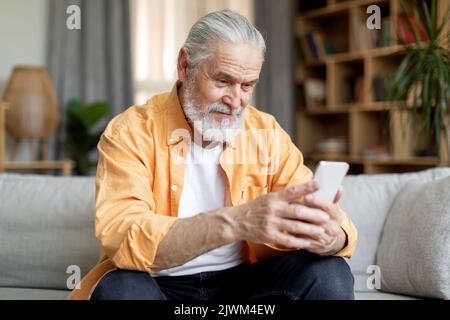 Happy senior man using smartphone at home Stock Photo