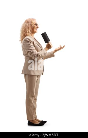 Full length profile shot of a female tv presenter with a microphone isolated on white background Stock Photo