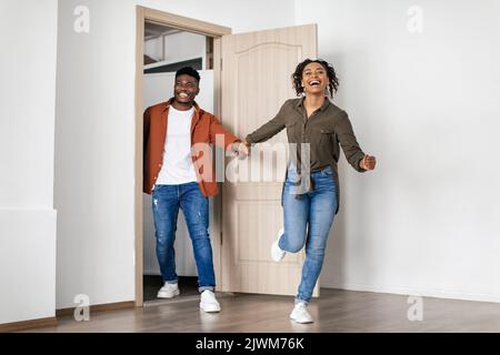 Excited African American Couple Running Into Room Entering New House Stock Photo