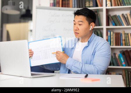 Chinese Teacher Male Having Online Class Via Laptop At Workplace Stock Photo