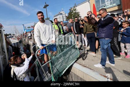 06 September 2022, Mecklenburg-Western Pomerania, Warnemünde: Rapper Marteria arrives with a historic tugboat at the Warnemünde pier, where he wants to give away about 500 fish rolls to his fans. With the action Marteria wants to make advertising for his stadium concert on 02.09.2023 in Rostock, because in addition to the rolls there were also codes for an advance sale of tickets. Photo: Bernd Wüstneck/dpa Stock Photo