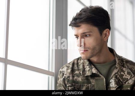 Serious young man soldier looking through the window Stock Photo