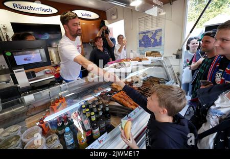 06 September 2022, Mecklenburg-Western Pomerania, Warnemünde: Rapper Marteria gives away about 500 fish rolls to his fans on the Warnemünde pier. With the action Marteria wants to make advertising for his stadium concert on 02.09.2023 in Rostock, because in addition to the rolls there were also codes for an advance sale of tickets. Photo: Bernd Wüstneck/dpa Stock Photo