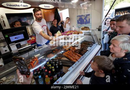 06 September 2022, Mecklenburg-Western Pomerania, Warnemünde: Rapper Marteria gives away about 500 fish rolls to his fans on the Warnemünde pier. With the action Marteria wants to make advertising for his stadium concert on 02.09.2023 in Rostock, because in addition to the rolls there were also codes for an advance sale of tickets. Photo: Bernd Wüstneck/dpa Stock Photo