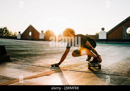 portrait of a man skateboarding in a car park at sunset Stock Photo