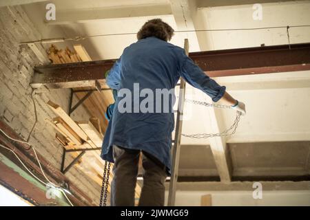worker hangs chain on steel beam. Construction staircase. Stock Photo