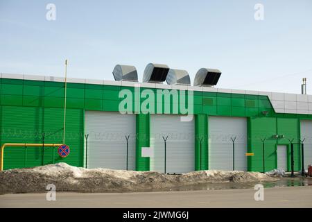 Garage for namesakes. Pipes on roof. Gate in house. Stock Photo