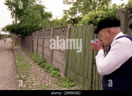 Bucharest, Romania, 1990. Man lighting up a cigarette outside his house in the Ferentari district. Stock Photo
