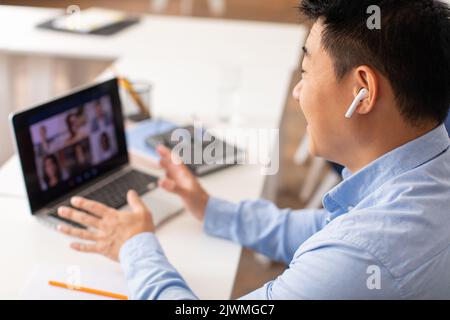 Korean Male Teacher Having Video Call Via Laptop At Workplace Stock Photo