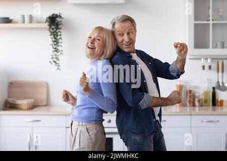 Joyful elderly spouses dancing together at kitchen Stock Photo