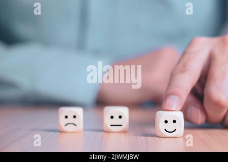 Businessman chooses a smile emoticon icons face happy symbol on wooden block , Services and Customer satisfaction survey concept Stock Photo