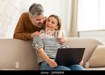 Happy Middle Aged Couple Using Laptop Computer At Home Stock Photo