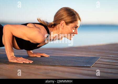 Athletic Middle Aged Woman Doing Plank Exercise Or Push Ups Outdoors, Closeup Stock Photo