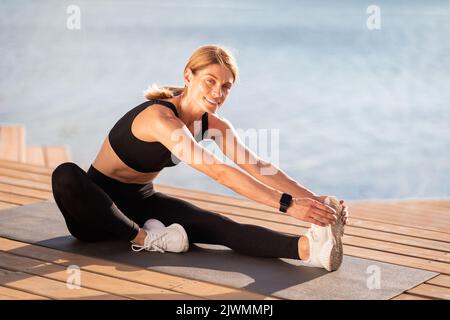 Outdoor Sports. Happy Fit Middle Aged Woman Doing Stretching Exercises Outside Stock Photo