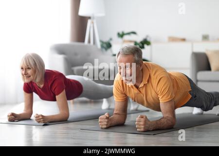 Cheerful senior couple having workout at home, planking Stock Photo