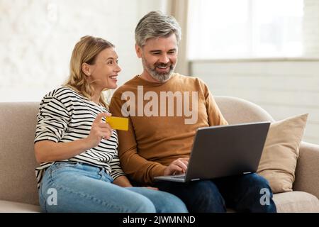 Couple Making Payment Using Laptop And Credit Card Shopping Indoor Stock Photo
