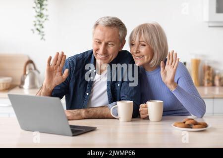 Cheerful elderly couple making video call while drinking coffee Stock Photo