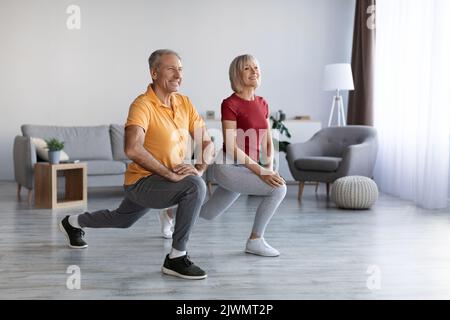 Positive mature couple having workout at home, copy space Stock Photo