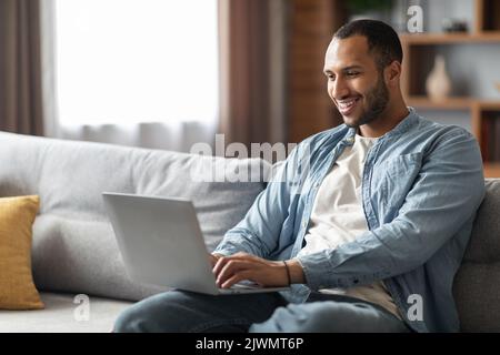 Remote Work. Handsome Young Black Freelancer Guy Using Laptop At Home Stock Photo