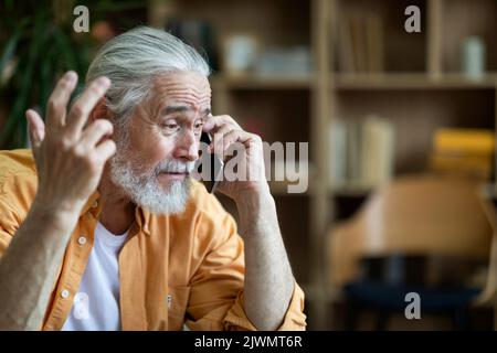 Emotional old man having phone conversation, gesturing Stock Photo