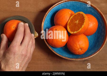 hand squeezing an orange to prepare juice Stock Photo