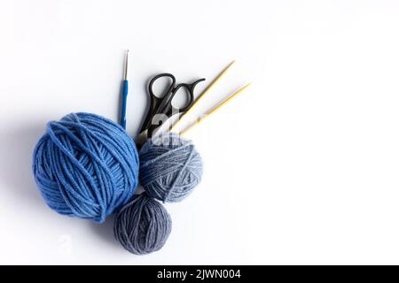 Blue balls of knitting thread with scissors, crochet and knitting needles on a white background for hobbies. Flat lay, isolated Stock Photo
