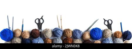Blue, gray and brown balls of knitting thread with scissors, crochet and knitting needles on a white background for hobbies. Flat lay, isolated Stock Photo