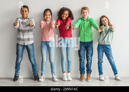Group Of Happy Diverse Children Gesturing Thumbs Up Indoor Stock Photo