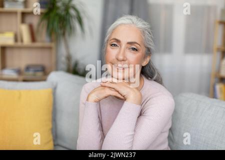 Smiling stylish confident attractive caucasian elderly gray-haired female looking at camera alone Stock Photo