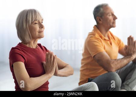 Closeup of senior man and woman practicing meditation together Stock Photo