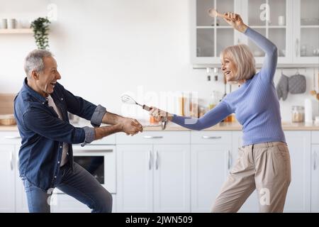 Loving senior couple enjoying time together in kitchen, having fun Stock Photo